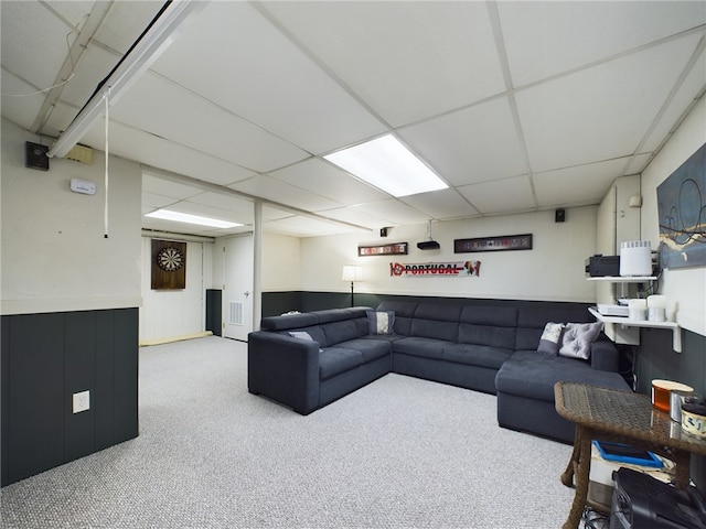 carpeted living area featuring a wainscoted wall and a drop ceiling