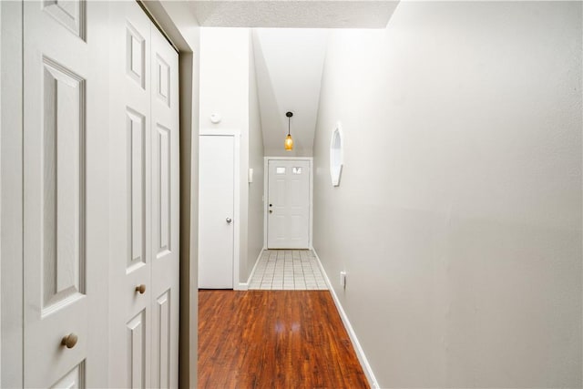 hall with baseboards and wood finished floors