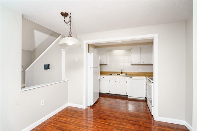 kitchen featuring light countertops, decorative backsplash, dark wood-type flooring, white appliances, and baseboards