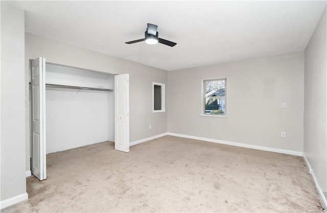 unfurnished bedroom featuring a closet, light colored carpet, ceiling fan, and baseboards