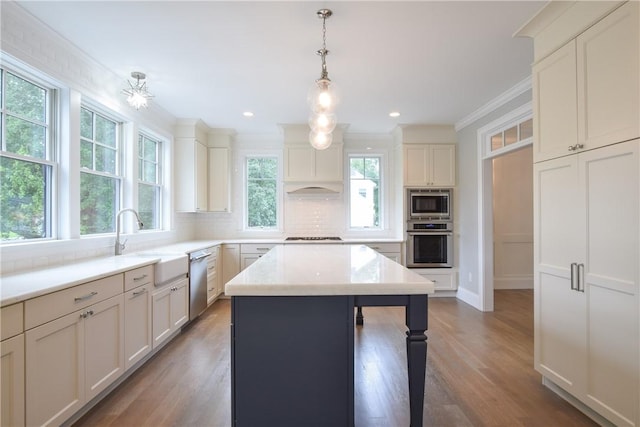 kitchen featuring stainless steel appliances, ornamental molding, a sink, and decorative backsplash