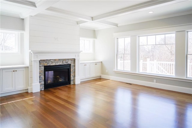 unfurnished living room featuring a wealth of natural light, visible vents, wood finished floors, and a stone fireplace