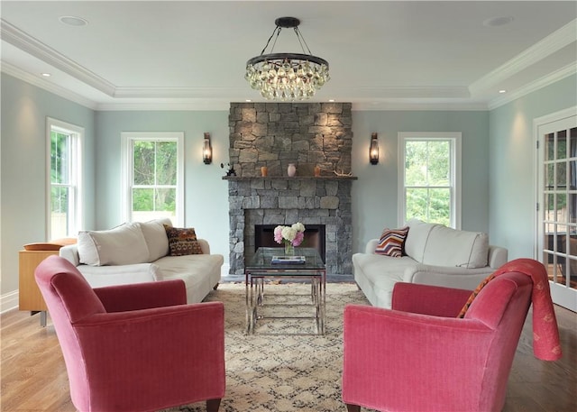 living room featuring crown molding, a fireplace, recessed lighting, a chandelier, and light wood-type flooring