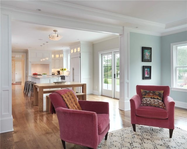 living area with ornate columns, light wood-type flooring, and crown molding