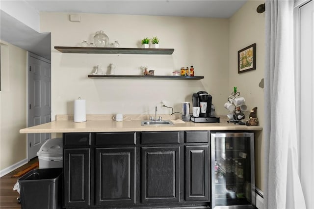 bar with beverage cooler, baseboards, wood finished floors, a sink, and indoor wet bar