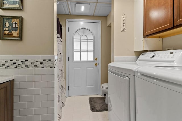 clothes washing area with a wainscoted wall, tile walls, and independent washer and dryer