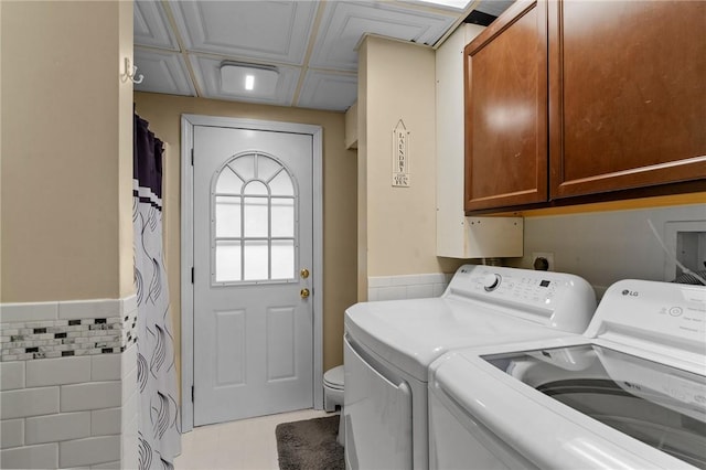 laundry area with a wainscoted wall, tile walls, and independent washer and dryer