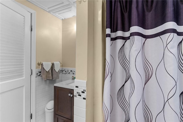 full bathroom featuring toilet, a wainscoted wall, tile walls, and vanity