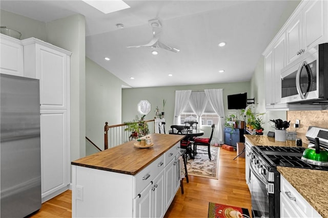 kitchen with stainless steel appliances, light wood-type flooring, white cabinets, and butcher block countertops