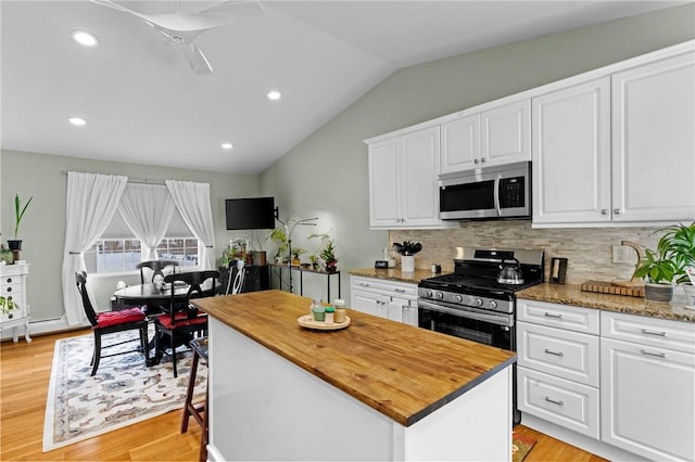 kitchen featuring lofted ceiling, appliances with stainless steel finishes, light wood-style floors, white cabinets, and butcher block countertops