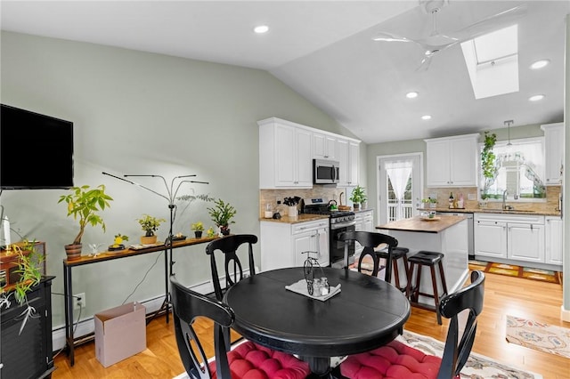 dining area with lofted ceiling with skylight, light wood-style flooring, and recessed lighting