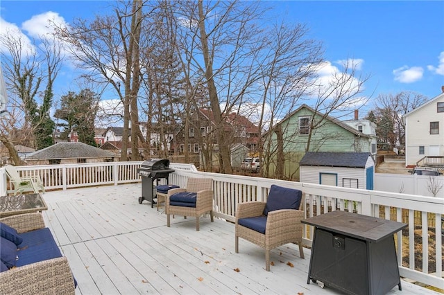 wooden deck with a storage unit, grilling area, an outdoor structure, and a residential view