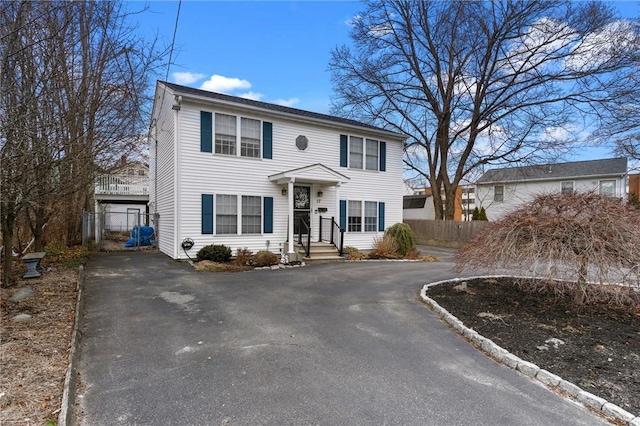 colonial inspired home with driveway and fence