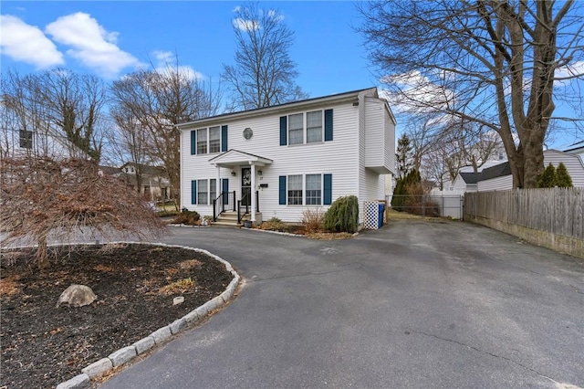 colonial home with aphalt driveway and fence