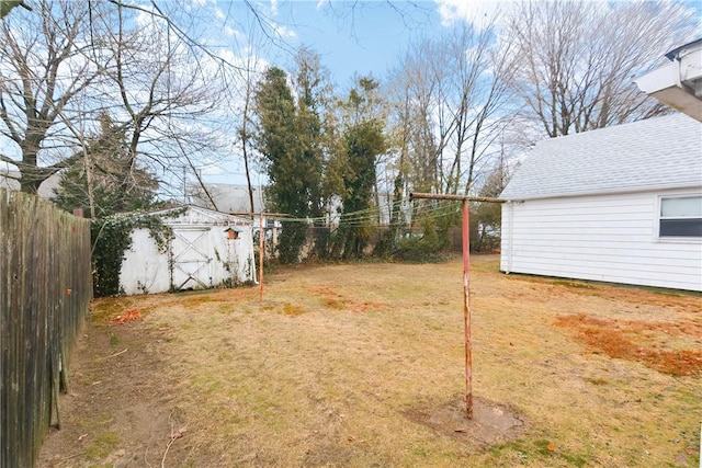 view of yard featuring an outbuilding, a storage unit, and fence