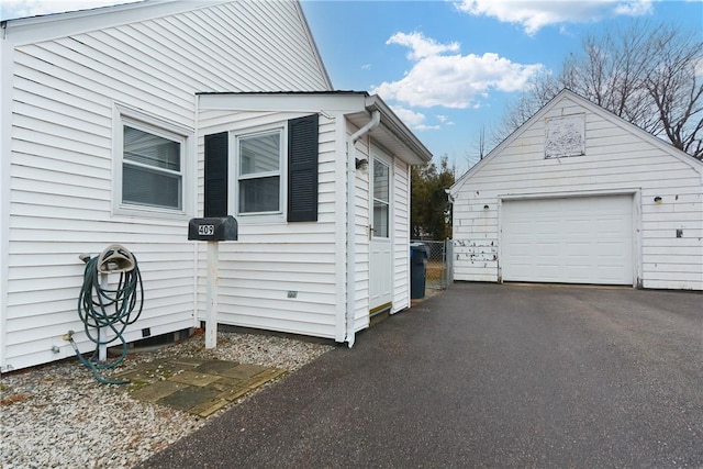 view of side of property with an outbuilding, a detached garage, and driveway