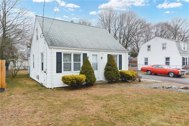 view of front of house featuring a front lawn, a shingled roof, and fence