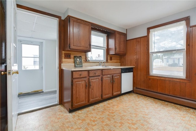 kitchen with a sink, light countertops, brown cabinets, dishwasher, and light floors