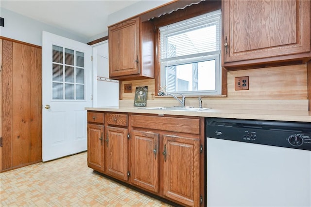 kitchen with light countertops, light floors, white dishwasher, and a sink