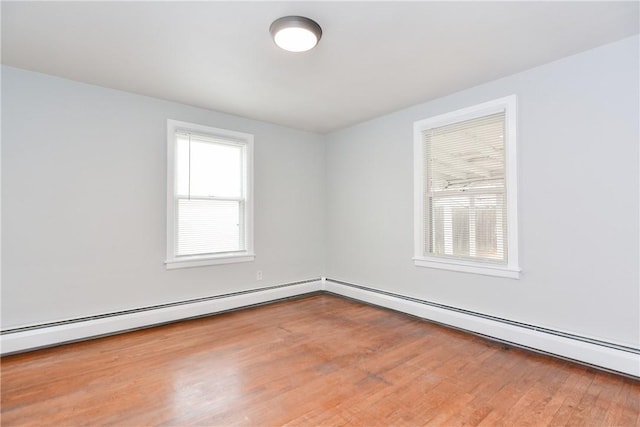 spare room featuring a baseboard heating unit and wood finished floors