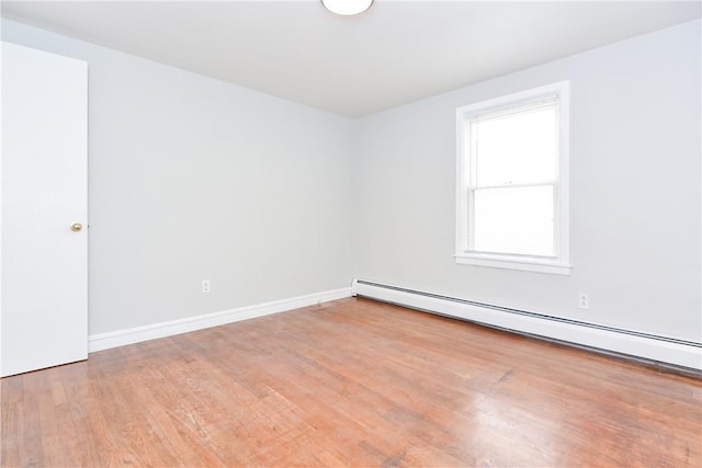 empty room featuring baseboards, baseboard heating, and wood finished floors