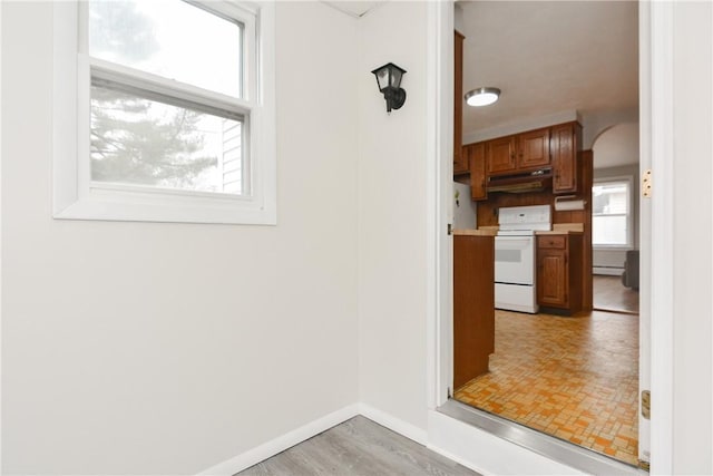 kitchen with arched walkways, white range with electric cooktop, plenty of natural light, and under cabinet range hood