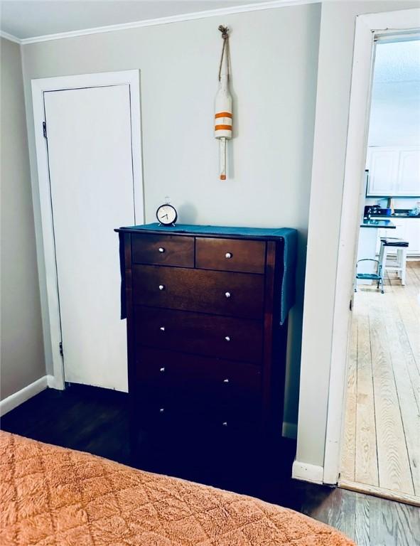 unfurnished bedroom featuring crown molding, baseboards, and wood finished floors