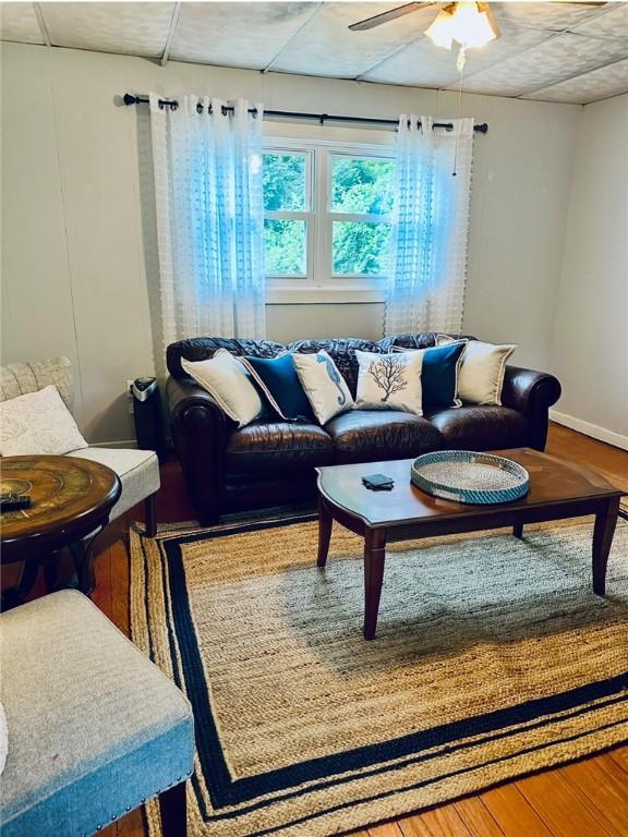 living room featuring ceiling fan, wood finished floors, and baseboards