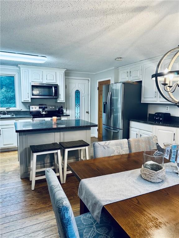 kitchen featuring appliances with stainless steel finishes, dark countertops, light wood-style flooring, and a breakfast bar