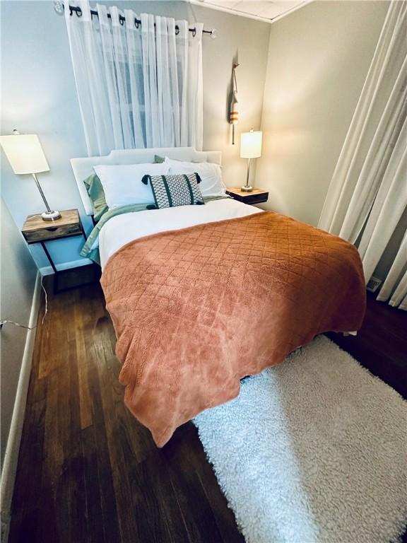 bedroom with crown molding, baseboards, and wood finished floors