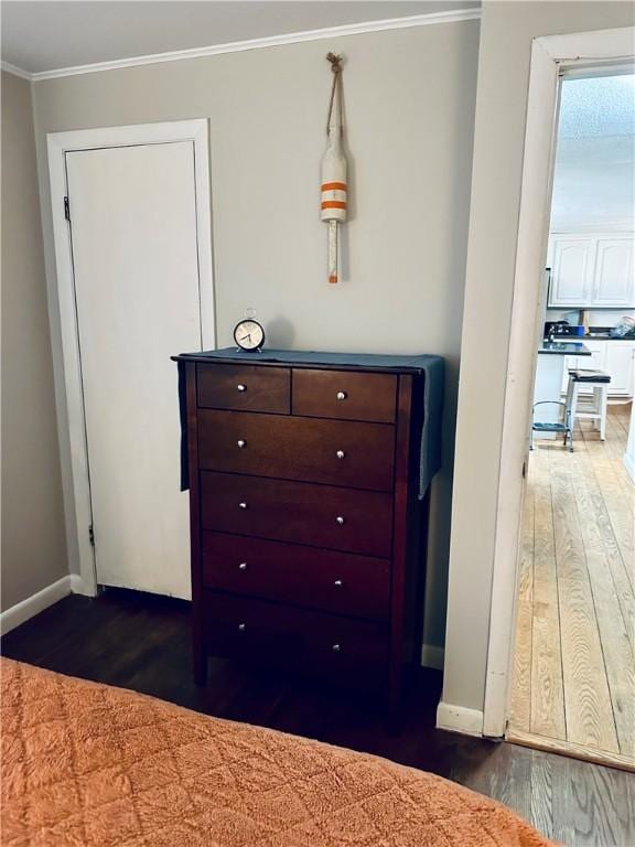 unfurnished bedroom featuring crown molding, baseboards, and wood finished floors