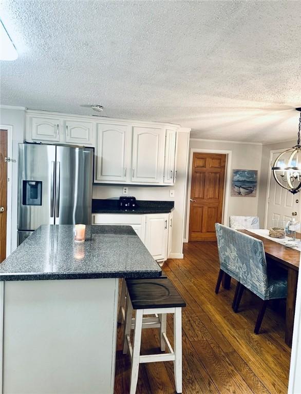 kitchen featuring dark wood finished floors, a chandelier, stainless steel fridge, and white cabinets