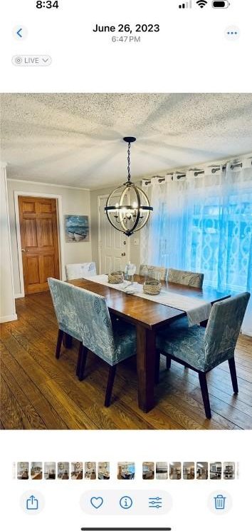 dining area with a textured ceiling, hardwood / wood-style floors, and an inviting chandelier