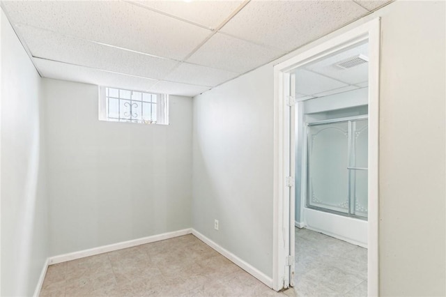 below grade area featuring visible vents, baseboards, and a drop ceiling