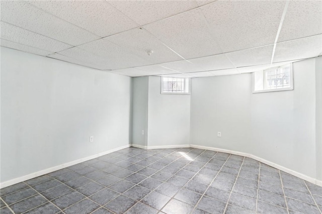 basement with baseboards, a paneled ceiling, and tile patterned flooring