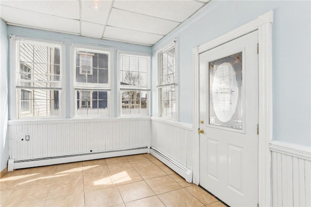 unfurnished sunroom featuring a drop ceiling and a baseboard radiator