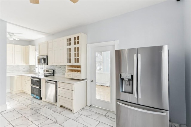 kitchen with marble finish floor, a ceiling fan, a sink, tasteful backsplash, and stainless steel appliances