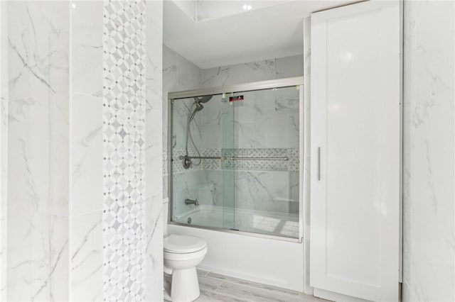 full bathroom featuring toilet, shower / bath combination with glass door, and wood finish floors