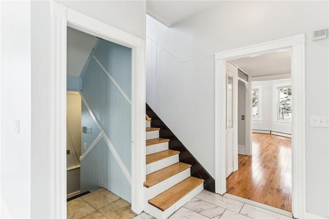 stairway with visible vents and baseboard heating