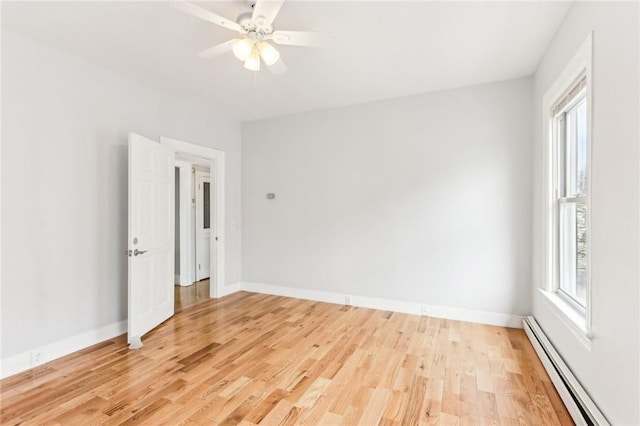 empty room featuring a wealth of natural light, baseboards, light wood-type flooring, and baseboard heating