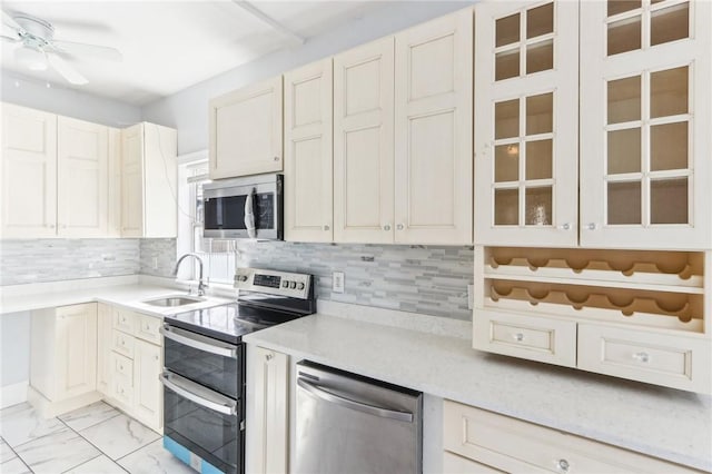 kitchen with tasteful backsplash, light countertops, appliances with stainless steel finishes, marble finish floor, and a sink