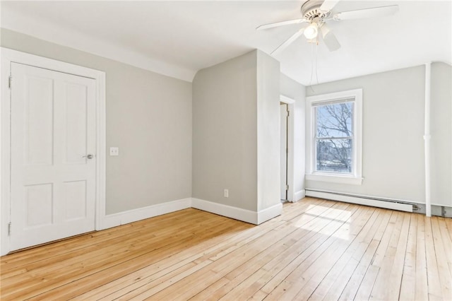 additional living space with hardwood / wood-style flooring, a ceiling fan, baseboards, and a baseboard radiator