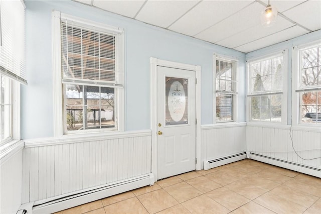 unfurnished sunroom with a drop ceiling, plenty of natural light, and baseboard heating