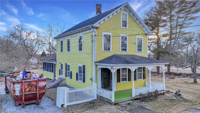 view of side of home featuring a chimney and a sunroom