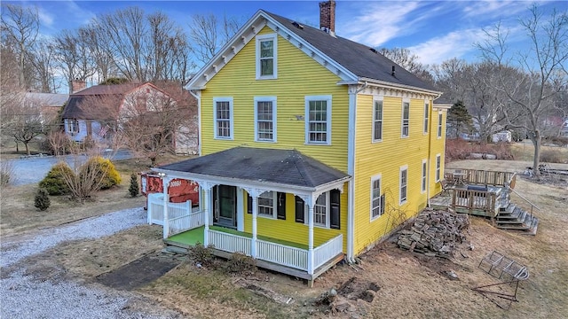 view of front of property featuring covered porch, roof with shingles, and a chimney