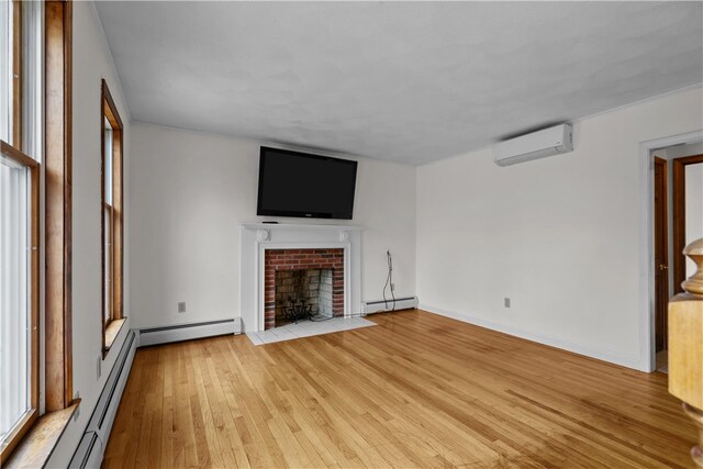 unfurnished living room featuring a baseboard heating unit, light wood-type flooring, a wall unit AC, and a fireplace