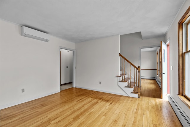 spare room with light wood finished floors, stairway, a wall mounted AC, a baseboard heating unit, and baseboards