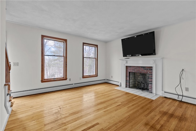 unfurnished living room featuring light wood-style flooring, a fireplace, and a baseboard heating unit