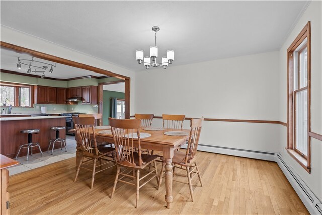 dining area with light wood-type flooring, a chandelier, baseboard heating, and track lighting