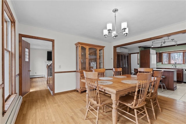 dining area with an AC wall unit, light wood-type flooring, a baseboard radiator, and a notable chandelier